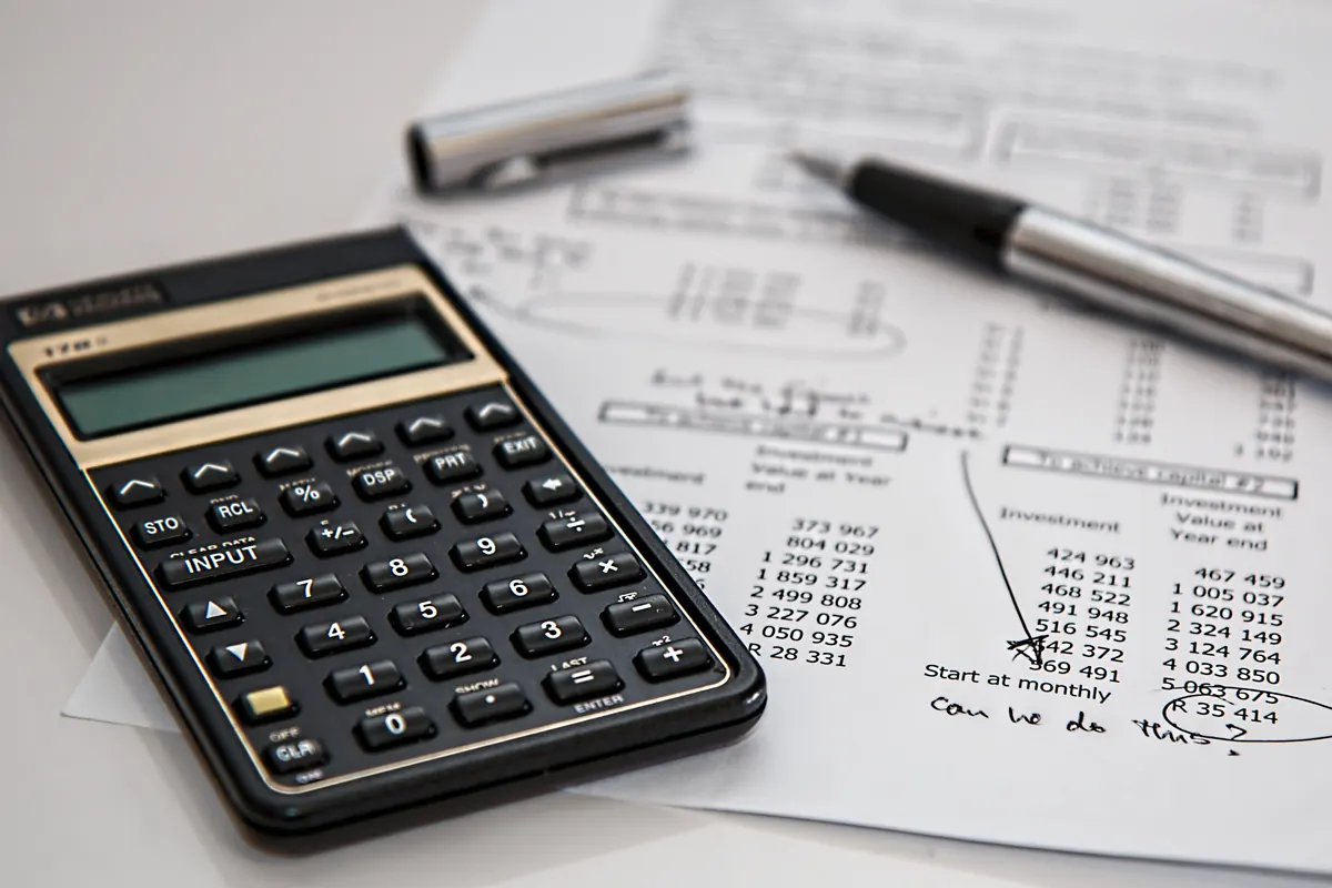 Calculator and pen resting on printed financial paperwork