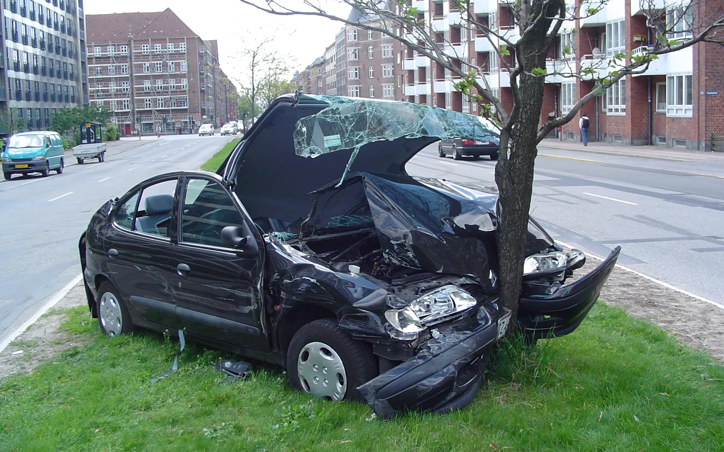 Two damaged vehicles beside a city street after a collision