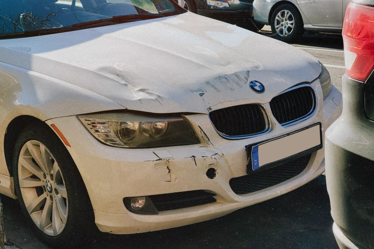Close view of collision damage across the front of a parked car