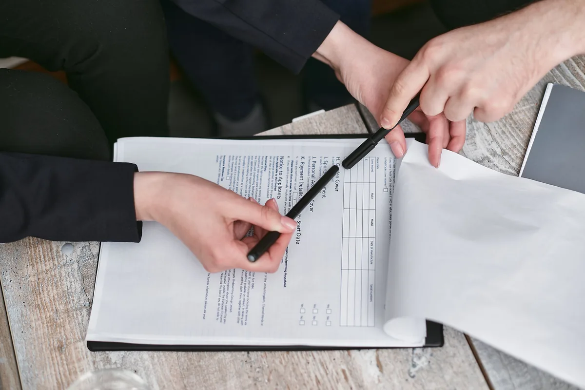 Two people reviewing paperwork together with pens