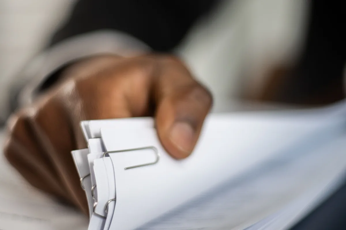 Person organizing a stack of documents with paper clips
